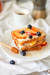 Breakfast on white bed sheets, good morning, summer french toast with cream cheese, honey, peaches and blueberries, coffee, flowers, Hotel room early morning, honeymoon