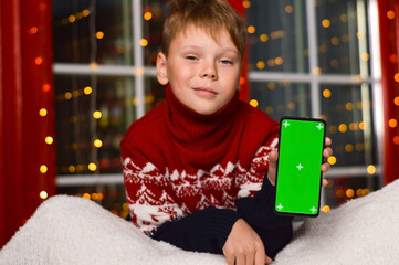 Child holding smartphone with green screen for modern technology on mockup template, watching...