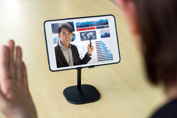 Back view of businessman in black suit have webcam conference through tablet computer with the investment advisor. Work from home concept