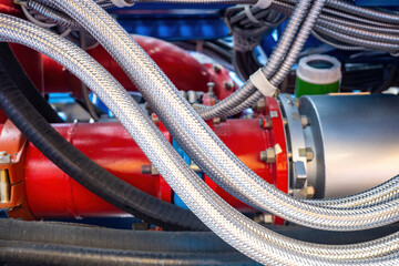 Fototapeta na wymiar Fragment of fire fighting equipment. Close-up of metal flexible hoses. Red steel pipes. Fire extinguishing equipment. Fire fighting technologies. Concept of production and sale of flexible hoses