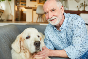 Alter Mann auf dem Sofa mit seinem Retriever Hund