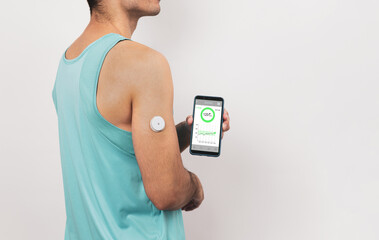 Unrecognizable young athlete shows his mobile with continuous glucose monitor blood sugar test app,...