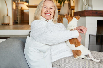 Glückliche Seniorin mit ihrem Schoßhund auf dem Sofa