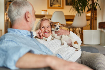 Senioren Paar sitzt mit ihrem Hund auf dem Sofa