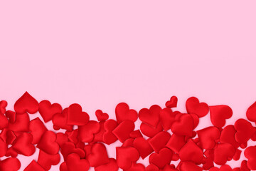 Red textile hearts confetti on a pink background. Place for text.