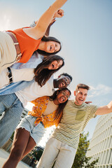 Vertical portrait of a Group of smiling multiracial teenagers having fun outdoors. Cherful young...