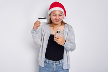 Sad young Asian woman in a Christmas hat holding mobile phone and blank white credit card isolated on white background