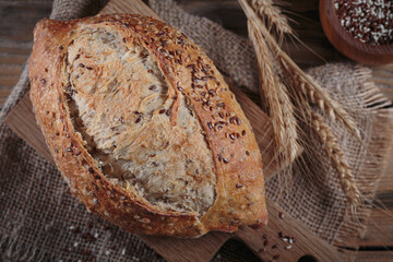 Fresh baked whole grain bread with oats, flax seeds and sesame seeds on rustic wooden board. Bakery products