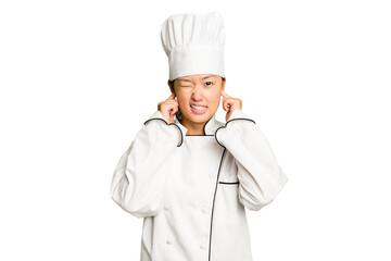 Young asian cook woman isolated covering ears with hands.