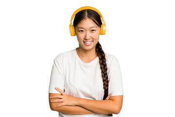 Young asian woman listening to music with headphones isolated laughing and having fun.