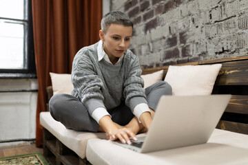 business woman working from home sitting with laptop on sofa