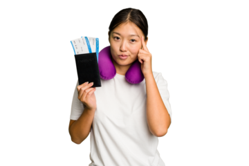Young asian woman with inflatable travel pillow on her neck holding passport isolated pointing temple with finger, thinking, focused on a task.