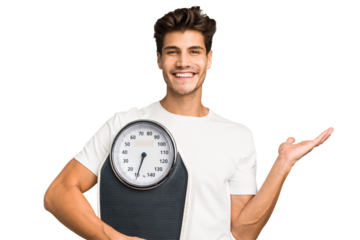 Young caucasian man holding a scale isolated showing a copy space on a palm and holding another hand on waist.