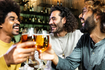 Happy multiracial friends drinking beer at brewery bar. Diverse young people celebrating together cheering with drinks at irish pub