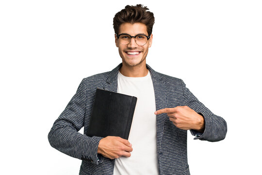 Young Teacher Caucasian Man Holding A Book Isolated Smiling And Pointing Aside, Showing Something At Blank Space.