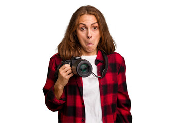 Young photographer caucasian woman isolated shrugs shoulders and open eyes confused.