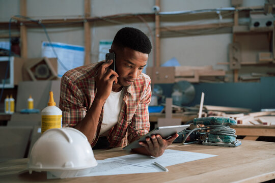 Young African carpenter planning and discussing on mobile phone