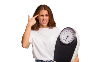 Young caucasian woman holding a scale and measure tape isolated showing a disappointment gesture with forefinger.