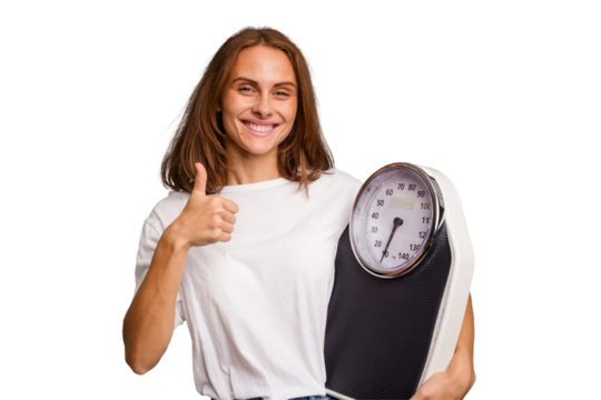Young caucasian woman holding a scale and measure tape isolated smiling and raising thumb up