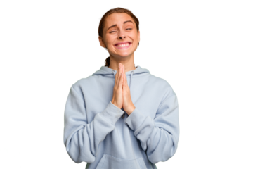 Young caucasian woman isolated holding hands in pray near mouth, feels confident.