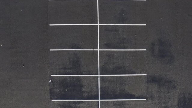 Aerial ascent from painted white lines in empty parkade parking lot