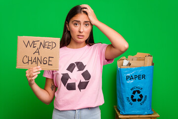 Young caucasian recycler woman holding a we need a change placard isolated being shocked, she has...