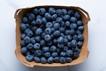 Fresh blueberry in delivery box on light surface
