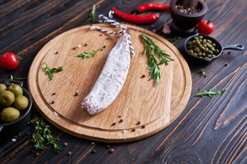 Spanish fuet salami sausageon wooden cutting board at domestic kitchen