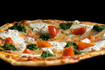 Close-up of a delicious pizza with tomatoes, herbs and mozzarella on a black background