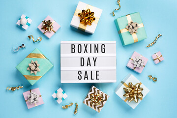 Fototapeta na wymiar White Lightbox and Holiday Festive Gift Boxes on Cyan Blue Background.