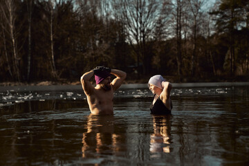 Caucasian couple standing and talking in frozen lake with hands raised