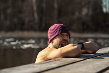 Caucasian adult man leaning in wooden pier in frozen lake