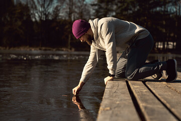 Caucasian adult man checking ice for swimming in frozen lake