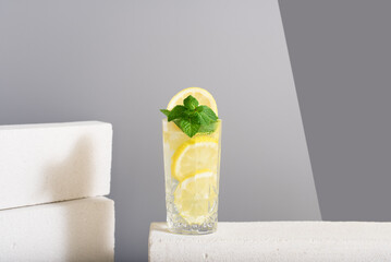 Zumo de limón con rodajas de limón y menta sobre fondo gris	
