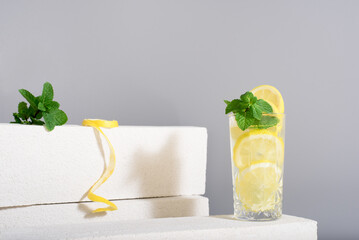 Zumo de limón con rodajas de limón y menta sobre fondo gris	