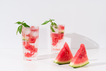 Dos vasos de zumo de sandía con trozos de sandia y hielo sobre fondo claro	