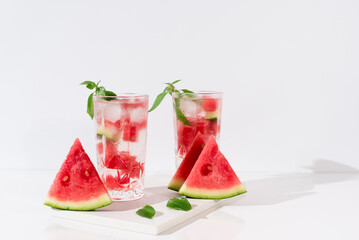 Dos vasos de zumo de sandía con trozos de sandia y hielo sobre fondo claro	