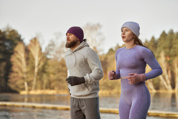 Adult caucasian couple running outdoors in the winter by the lake