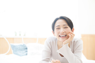 メインビジュアルにも！寝そべって微笑む美しい笑顔の女性 カメラ目線