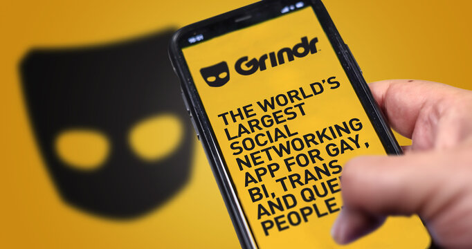 hand holding a phone with Grindr mobile application on screen
