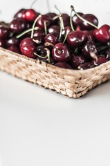 Wicker basket with fresh fragrant cherry on a white background.