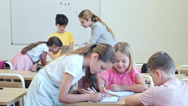 Interested preteen pupils divided into small groups, discussing learning material in classroom. Group work as effective teaching method