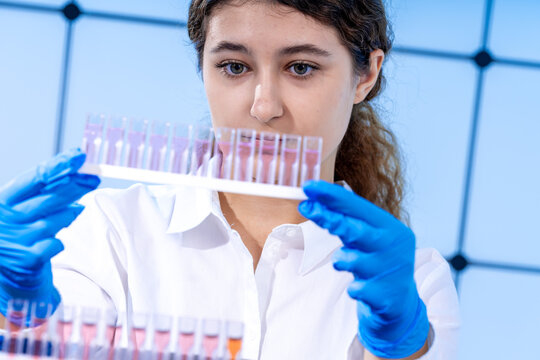 young woman in a microbiological laboratory is examining cuvettes for optical analysis of the properties of a liquid