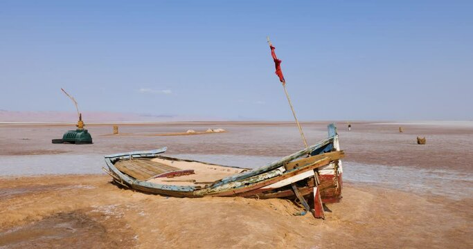 Salt lake in Tunisia Chott el Djerid during a sunny windy day. Largest salt lake in the Sahara Desert. Tourist destination. Travel the world. Boat on the dry lake. Mysterious landscape. 