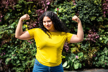 Young multiracial woman flexing muscles and looking at camera