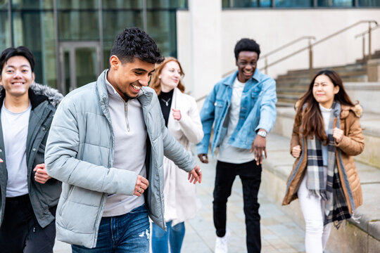 Multiracial friends running and enjoying time together at city or university
