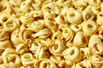 Tortellini pasta with prosciutto food background. Italian stuffed pasta