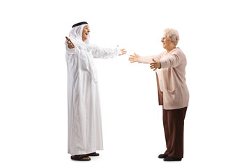 Full length profile shot of a mature arab man in a robe greeting an elderly lady