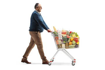 Full length profile shot of a mature man walking with food in a shopping cart
