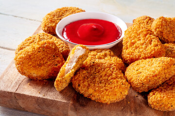 Chicken nuggets with ketchup close-up on a wooden board. A crispy snack at a restaurant, a fast food dish